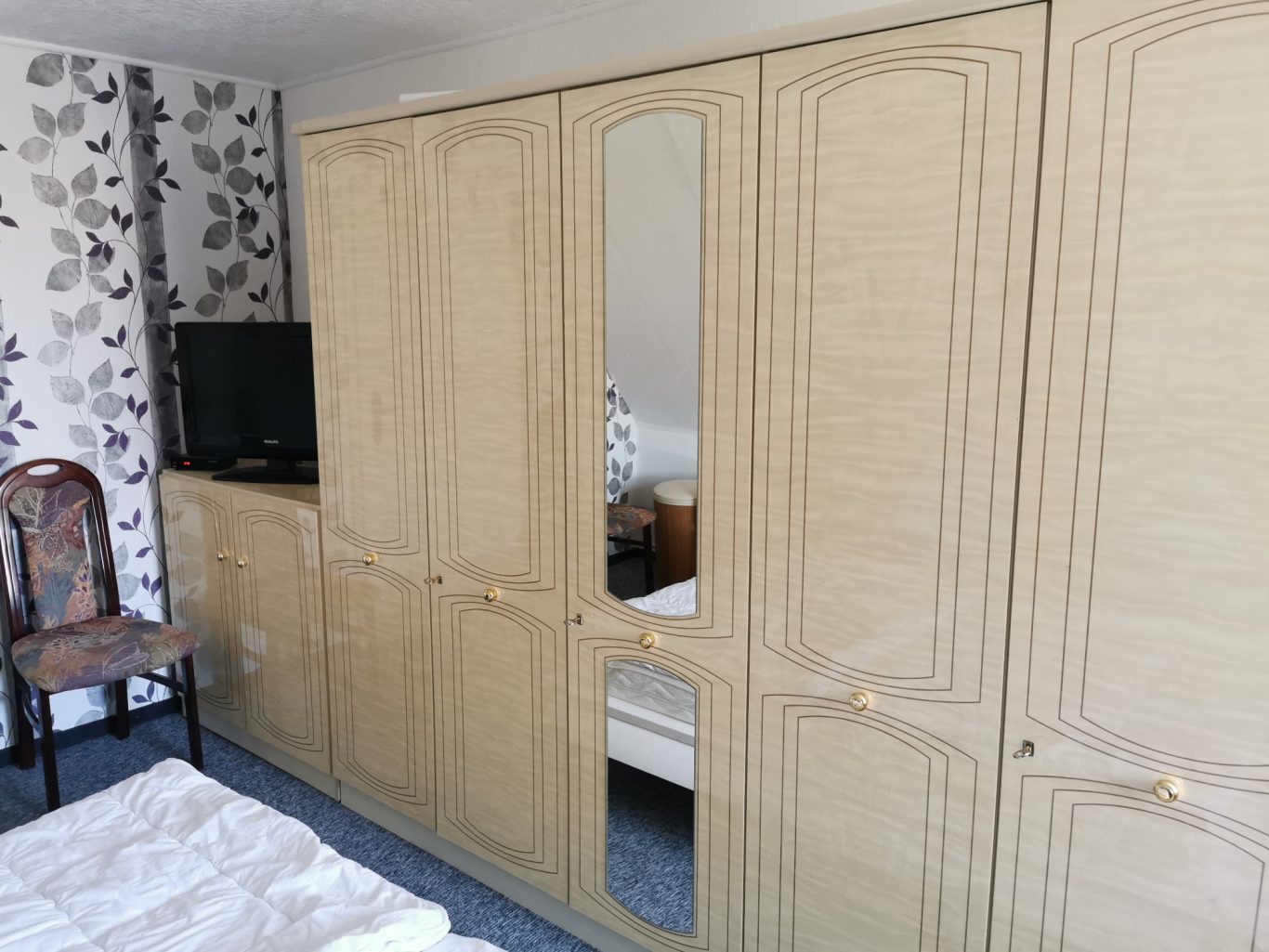 Ein Schlafzimmer mit einem großen Holzkleiderschrank und einem Fernseher auf einem Sideboard.